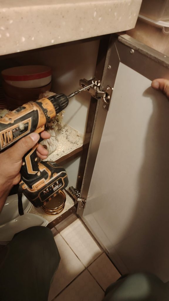 فني يقوم بتصليح مفصلات المطبخ في جدة مع ضبط أبواب الخزائن بشكل دقيق